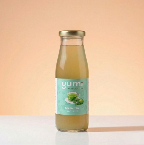 Bottle of yumi kombucha green tea and mint flavor on a peach background