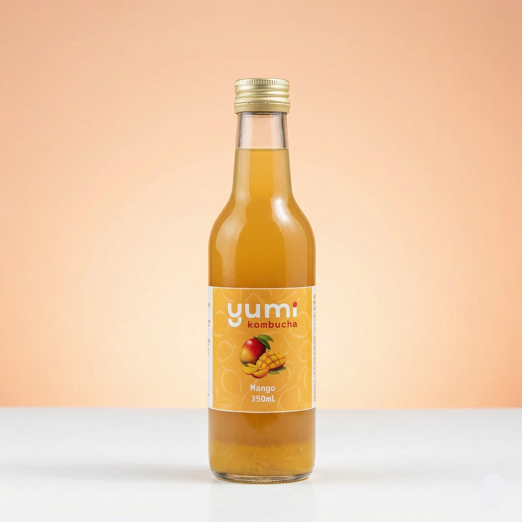 Bottle of yumi kombucha with a mango flavor on a peach background