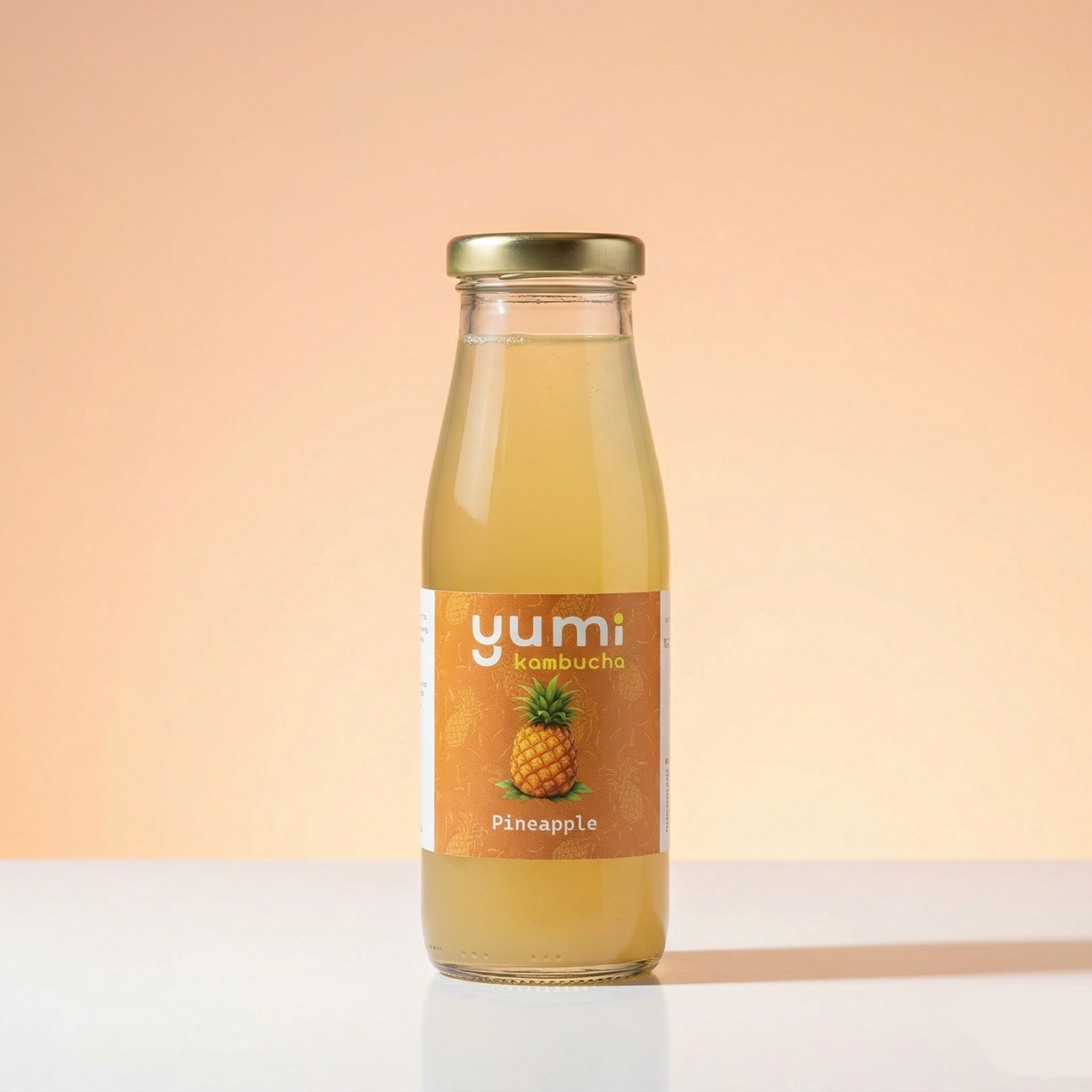 Bottle of yumi pineapple kombucha on a peach background